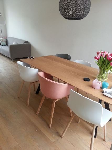 Τραπεζαρία με παστέλ ροζ και λευκές καρέκλες.